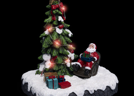 Pueblo navideño brillante "Papá Noel" en su sillón alrededor de un árbol - 183250